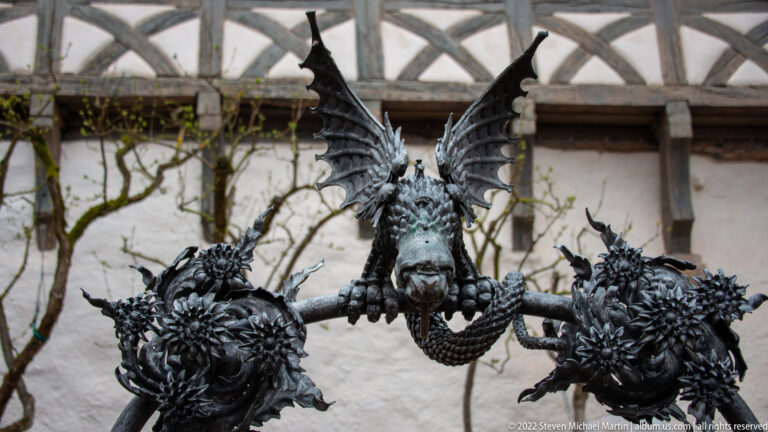 Three dark metal dragon sculptures perched on branching supports, with the central dragon spreading large wings.