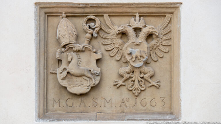 Stone relief with two coats of arms, one with a mitre and crozier and one with a double-headed eagle, dated 1663.