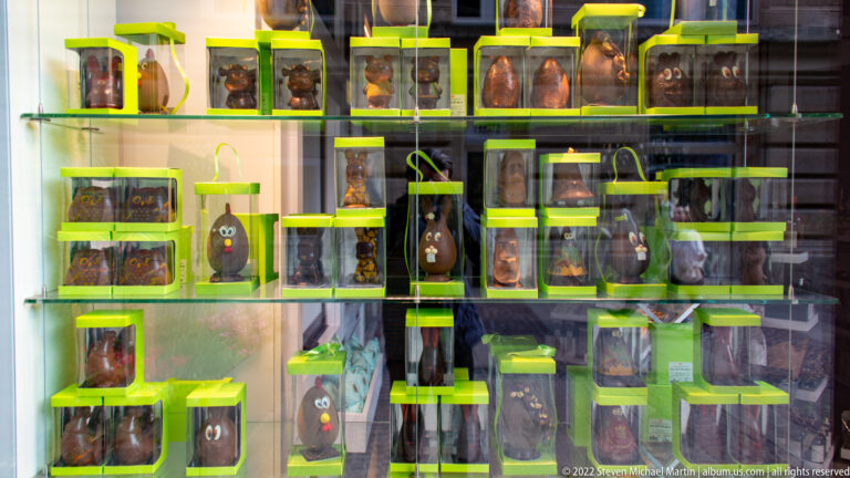 Shop window filled with novelty chocolate figures and boxed confections in bright lime-green packaging.
