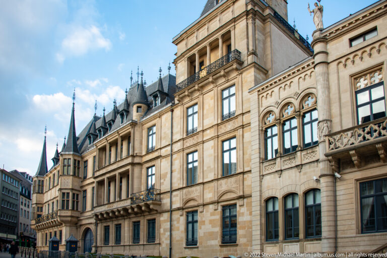 Grand Ducal Palace façade with carved stonework, projecting bays, mullioned windows, balconies, and pointed roof turrets.