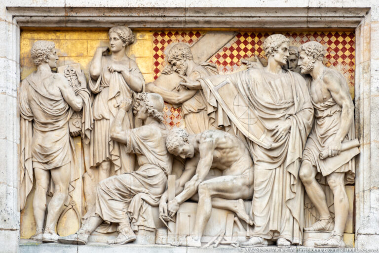 Stone relief of multiple draped figures against a red-and-gold patterned background on the Rijksmuseum façade.