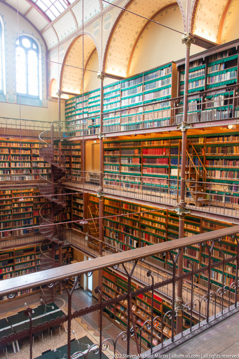 Rijksmuseum Cuypers Library with multilevel bookcases, iron galleries, columns, and a decorated arched ceiling.