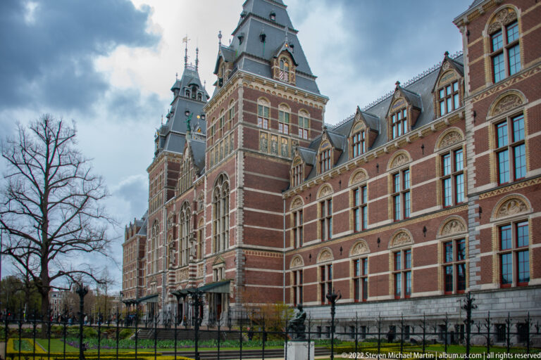 Oblique view of the Rijksmuseum's red-brick and stone exterior with towers, dormers, and arched windows.