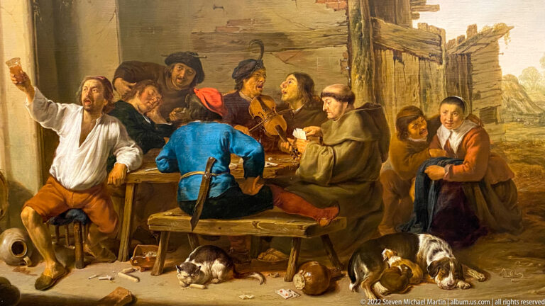 Rustic tavern painting with men drinking and playing cards around a table, with dogs and scattered objects.