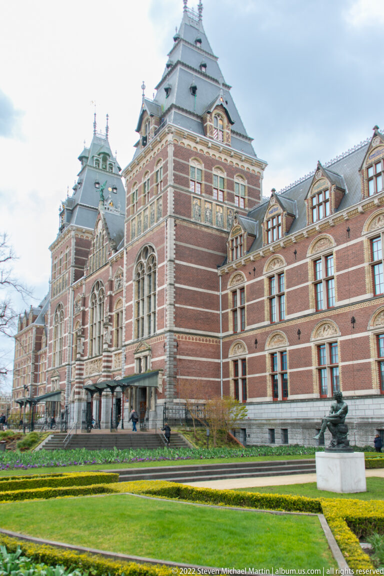 Rijksmuseum red-brick façade beyond clipped lawns and geometric garden beds.