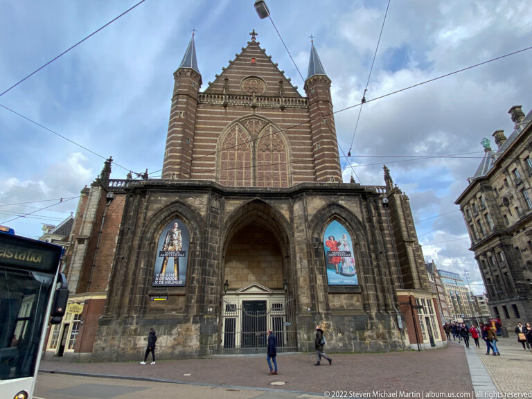 Nieuwe Kerk Gothic façade with large traceried window, pointed entrance arch, corner turrets, and exhibition banners.