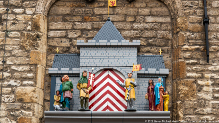 Polychrome figurine tableau on Gouda Town Hall with costumed figures, miniature architecture, and red-and-white heraldic stripes.