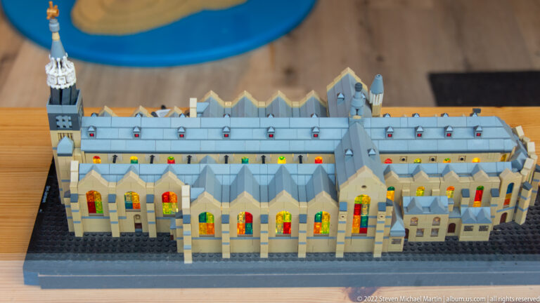 LEGO-style model of a long Gothic church with tower, repeated bays, and colored windows.