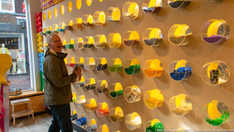 Visitor standing beside a wall of round transparent bins filled with colorful sweets.