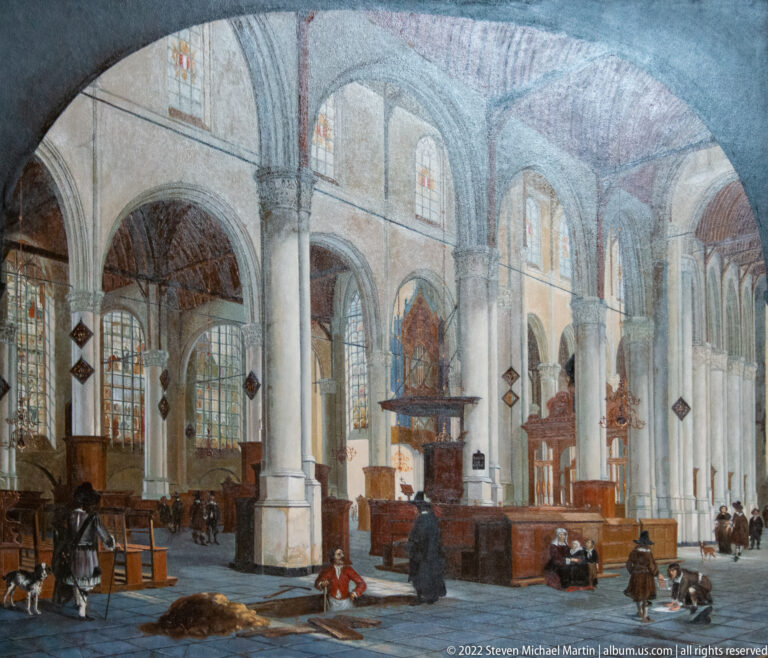 Historic interior view of Sint-Janskerk with tall columns, arcades, wooden furnishings, and people in the nave.