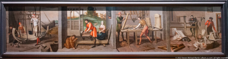 Long painted panel divided into workshop scenes with figures, tools, benches, and timber.