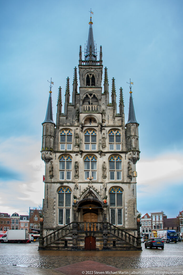 Frontal view of Gouda Town Hall on the Markt, with Gothic stone façade, corner turrets, pinnacles, and central stair.