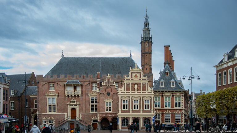 Historic brick façades of Haarlem City Hall on Grote Markt, with varied gables, arched openings, and pedestrians in front.