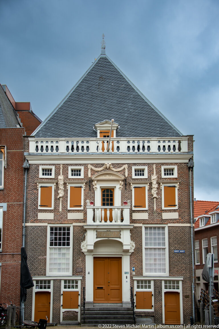 Symmetrical brick façade of the Hoofdwacht with pale stone trim, shuttered windows, central doorway, balcony, and hipped roof.