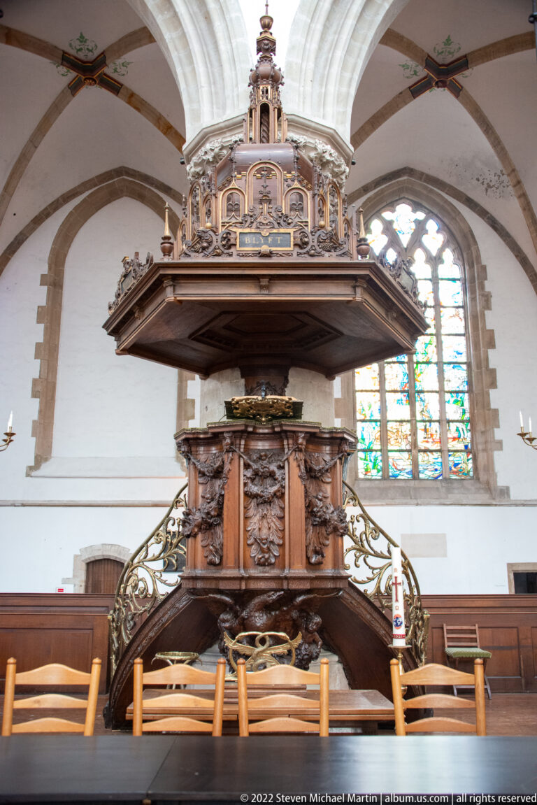 Carved wooden pulpit with sounding board and stair inside the whitewashed Gothic interior of Haarlem’s Grote Kerk.