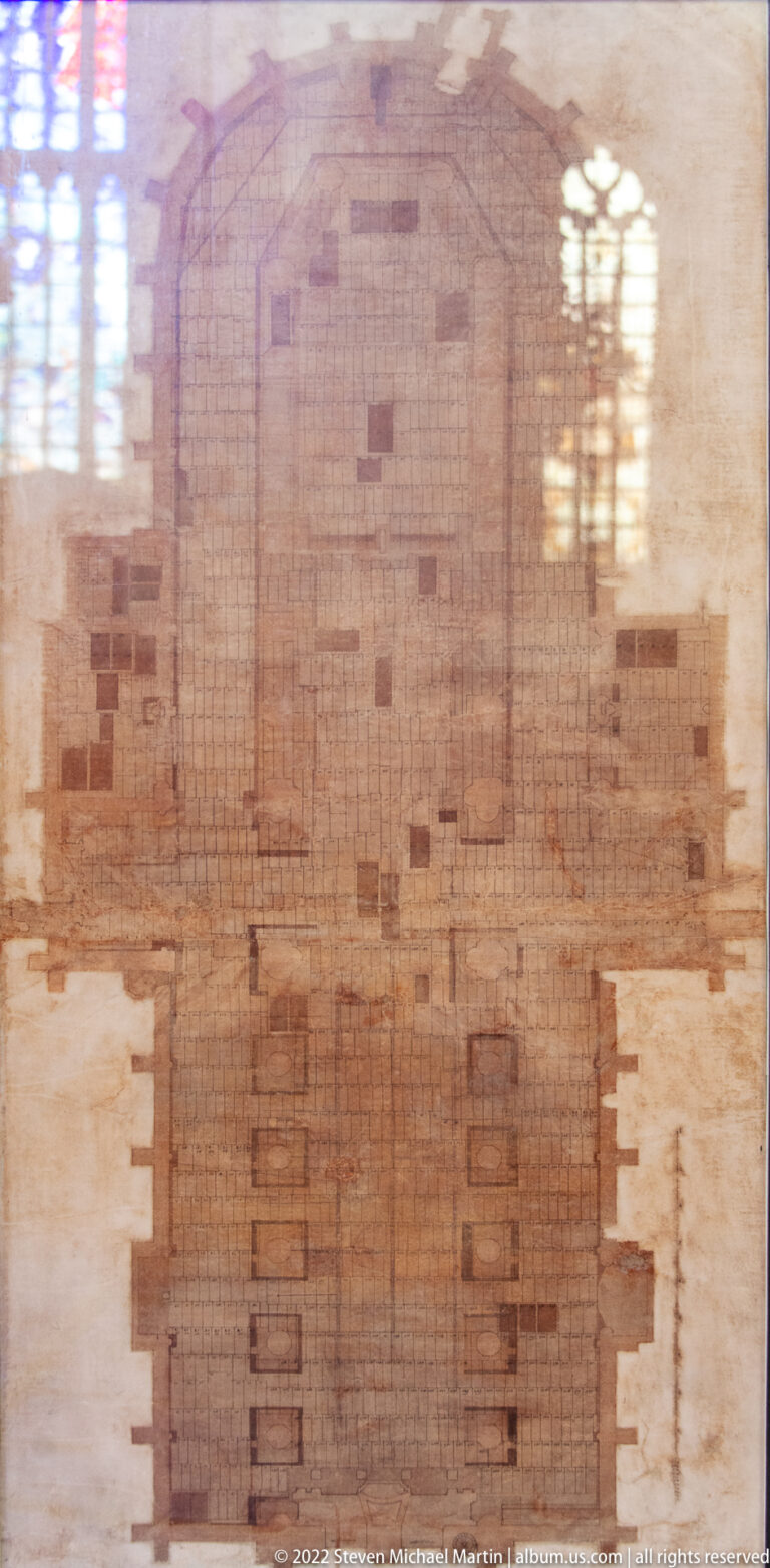 Large worn rectangular stone or tile surface in the church floor, divided into an irregular grid with window reflections.