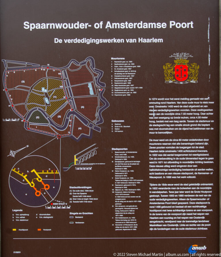 Outdoor interpretive sign with a map of Haarlem’s fortifications, Dutch text, heraldic shields, and a diagram of the Amsterdamse Poort.