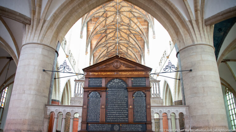 Large architectural wall memorial with pediment and dark inscribed panels standing between stone columns under a vaulted roof.