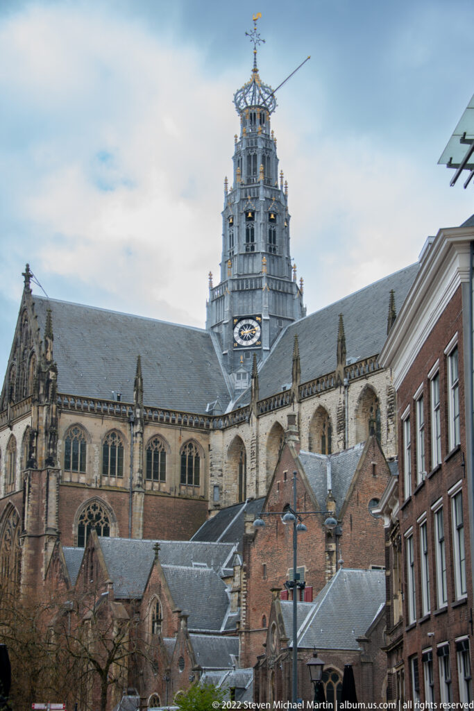 Side view of Haarlem’s Grote or St.-Bavokerk with Gothic windows, buttresses, rooftops, and the tall openwork crossing tower.