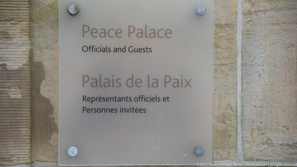 Metal wall sign reading “Peace Palace Officials and Guests” and the equivalent French text “Palais de la Paix.”