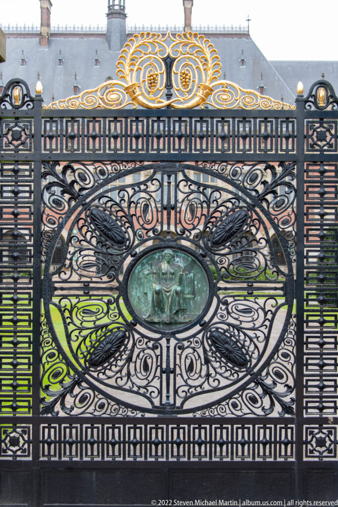Central Peace Palace gate panel with black scrollwork, green oval medallion, and gilded crest above.