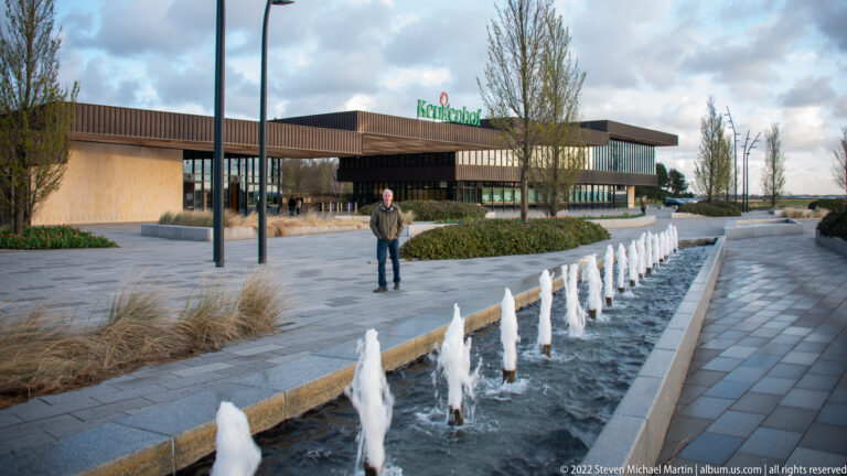 Linear fountain with white jets leading toward the Keukenhof entrance, with one visitor standing beside the water.