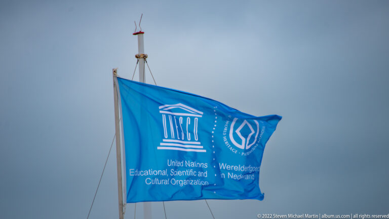 Blue UNESCO World Heritage flag flying against a gray sky.