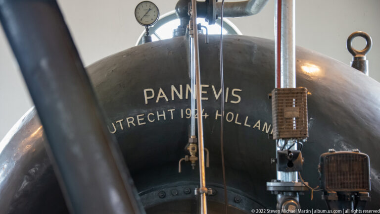 Curved metal vessel labeled PANNEVIS, UTRECHT 1944 HOLLAND, surrounded by pipes, gauges, and fittings.