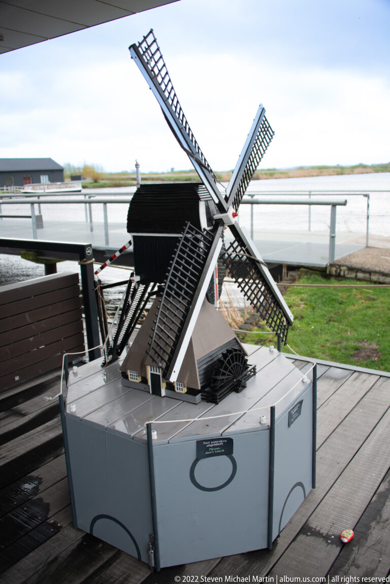 Detailed model of a Dutch windmill with four latticed sails on a raised display base.
