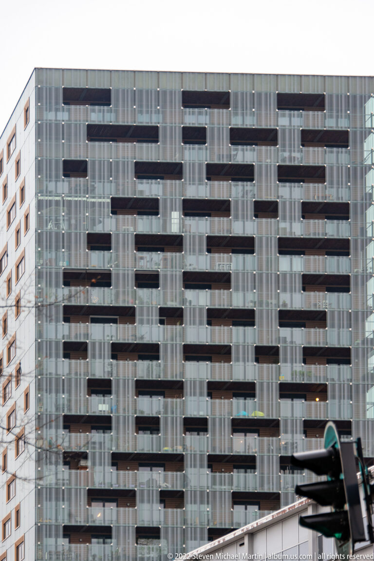 Modern high-rise façade with staggered dark balconies set against a pale glass and structural grid.