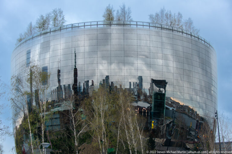 Rounded mirrored Depot Boijmans Van Beuningen behind trees, reflecting surrounding buildings across its lower façade.