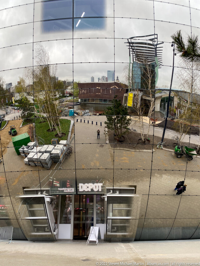 Museumpark plaza and DEPOT entrance reflected across the curved mirrored façade of Depot Boijmans Van Beuningen.