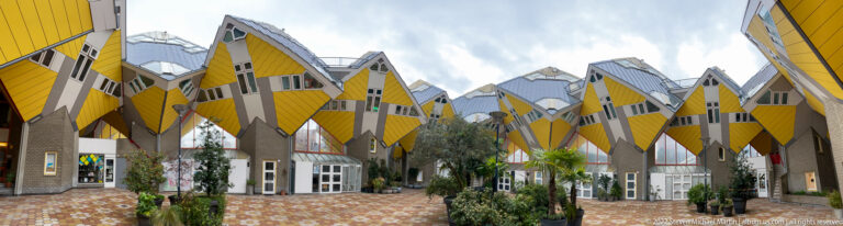 Courtyard beneath Rotterdam’s yellow Cube Houses, with tilted volumes, angular windows, gray supports, and potted plants.