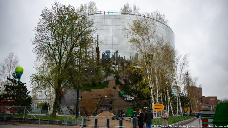Mirrored Depot Boijmans Van Beuningen behind birch trees, fencing, soil piles, and Museumpark construction works.