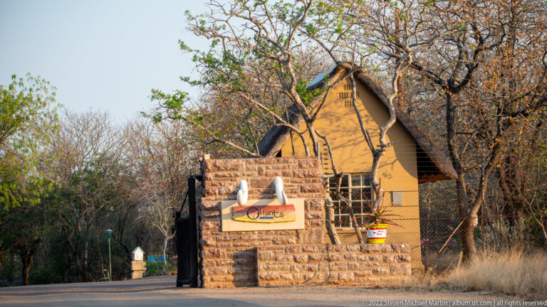 Stone sign marked Olifants beside a thatched building at the entrance to Olifants Rest Camp.