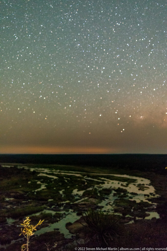 Star-filled night sky above the dark Olifants River floodplain, with faint pale channels visible below.