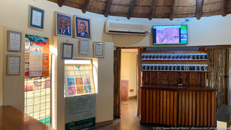 Punda Maria reception interior with wooden counter, information displays, framed certificates, maps, and television screen.