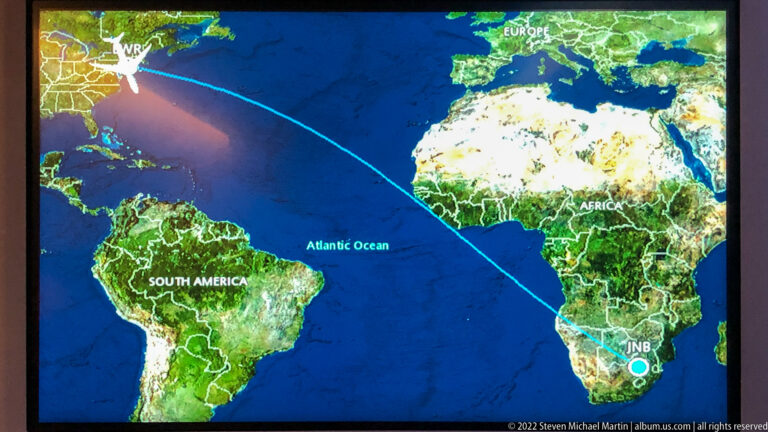 In-flight world map showing a blue transatlantic route from North America to Johannesburg, South Africa.