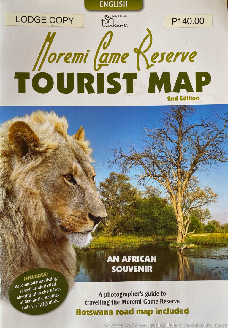 Cover of a Moremi Game Reserve tourist map featuring a lion portrait, wetland landscape, and large green title text.