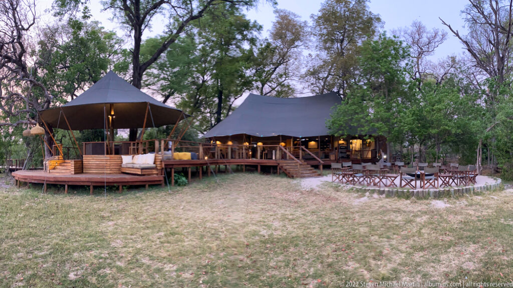 Wide dusk view of Stanley’s Camp with raised canvas pavilions, wooden decks, outdoor tables, and surrounding trees.