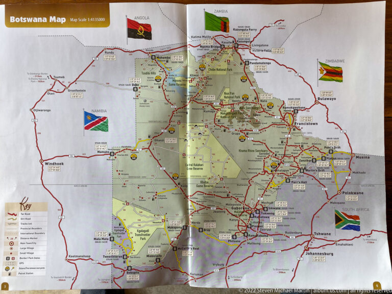 Folded southern Africa road map showing Botswana and neighboring countries with routes, towns, flags, and park areas.
