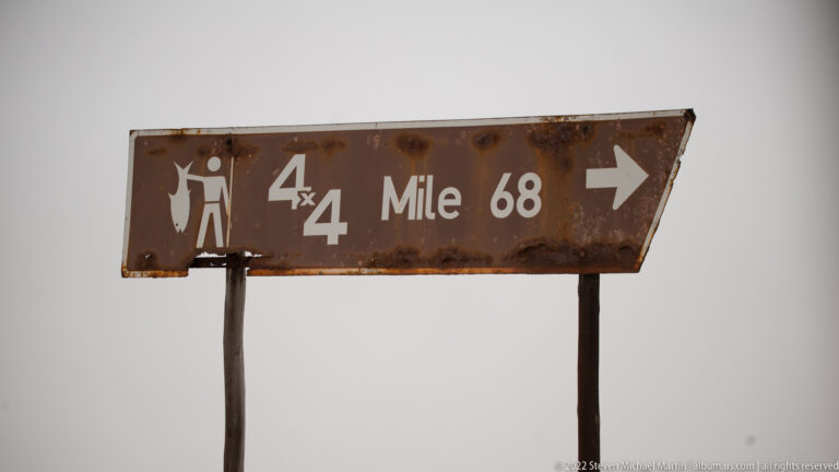 Weathered brown sign reading 4x4 Mile 68 with a right arrow and angling pictogram.