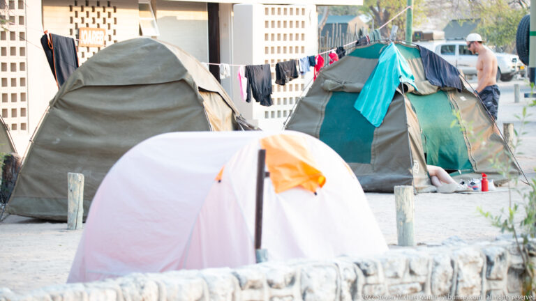 Cluster of dome tents with drying clothes and a camper in the Okaukuejo campsite.