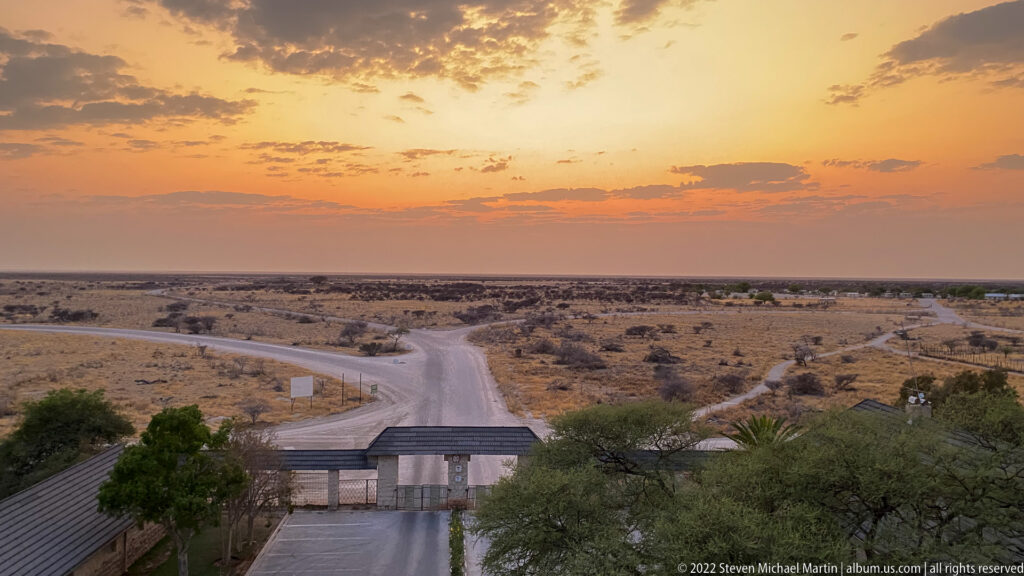 Sunrise over a branching road junction leading from Okaukuejo into flat Etosha scrubland.