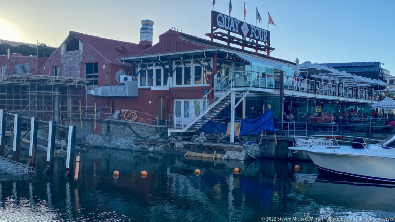 Red Quay Four restaurant on the harbor edge with exterior stairs, terraces, and a moored boat.