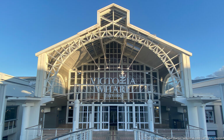 Wide view of Victoria Wharf’s gabled entrance hall with white steel trusses, glass façade, and central doors.