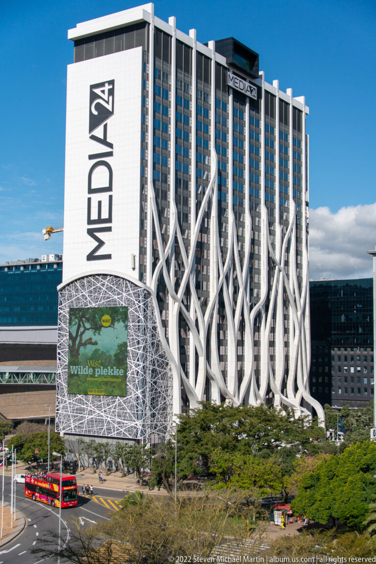 Tall Hotel Sky building with large vertical signage and branching white façade structures above a city street.
