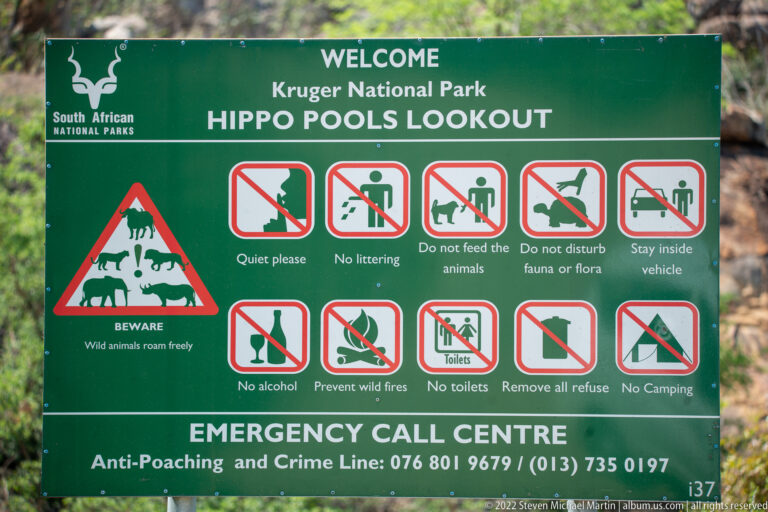 Green Hippo Pools Lookout sign with wildlife warning, visitor rules, pictograms and emergency contact numbers.