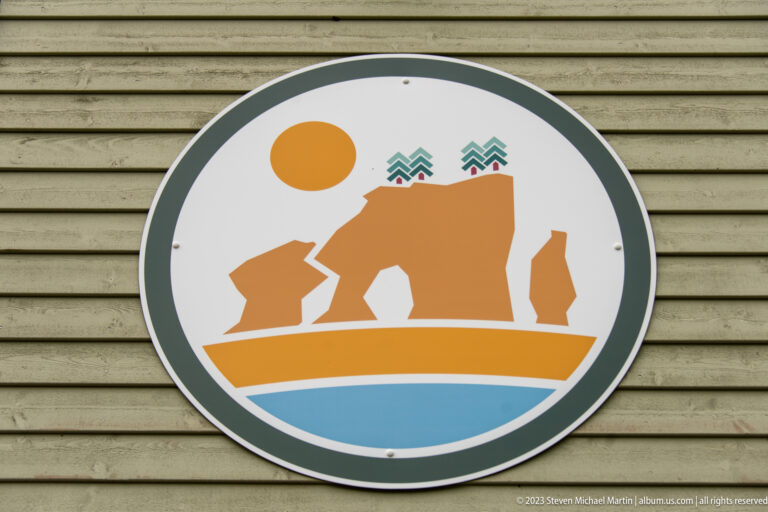 Circular Hopewell Rocks emblem showing stylized sea stacks, orange shore, blue water, and trees.