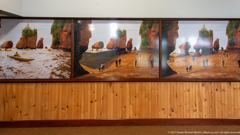 Large wall photographs showing visitors walking among Hopewell Rocks sea stacks at low tide.
